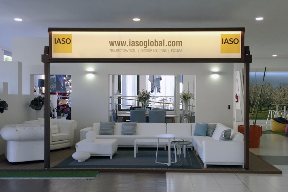 Pérgola de color marrón con un retroiluminada con la web de IASO y dos logos